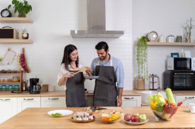 Romantik çift mutfakta yemek pişiriyor. Yakışıklı bir adam ve çekici genç bir kadın salata yaparken birlikte eğleniyorlar. Sağlıklı yaşam tarzı kavramı.