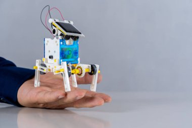 Bir plastik robot, masaya yerleştirilmiş bir öğrencinin elinde, elleriyle öğrenme ve yeteneklerini geliştirme konusunda deneyler yapıyor. Okul güneş enerjili navigasyon için kod yazıyor