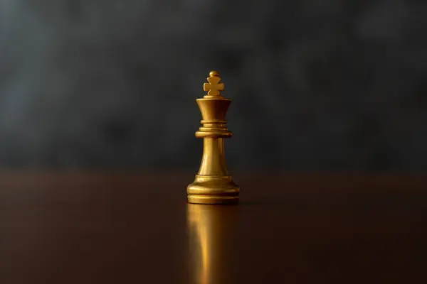 Close up the golden queen chess piece standing alone on a chessboard on dark background. Leader, influencer, lonely, commander, strong, and business strategy concept.