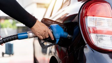 Man driver hand refilling and pumping gasoline oil the car with fuel at he refuel station. Car refueling on petrol station. Fuel pump at station. Refueling the car at a gas station fuel pump.