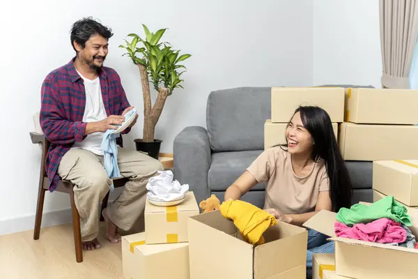 Couple recycle, donate and packing boxes for relocation while moving house for sustainability and eco friendly lifestyle. Saving environment with zero waste for a green, clean and happy future.