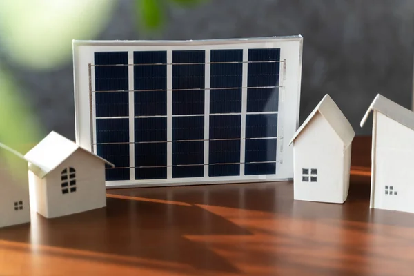 On desk of engineers lay model of house And solar panels to use in planning installation of solar panels to house in order to get most cost effective energy from installing solar panels.