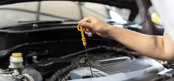Woman checking car engine oil in the shade working, checking car engine oil. Woman taking care of car Check car engine oil concept. Wide banner image.