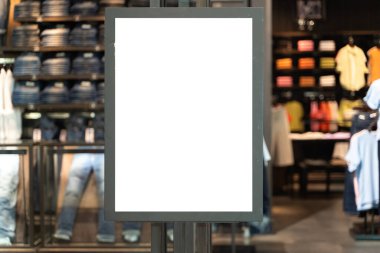 Cam pencereli bir giyim mağazasının önünde dikey beyaz tabela var. Alışveriş merkezindeki indirimli tabela mağazası. 