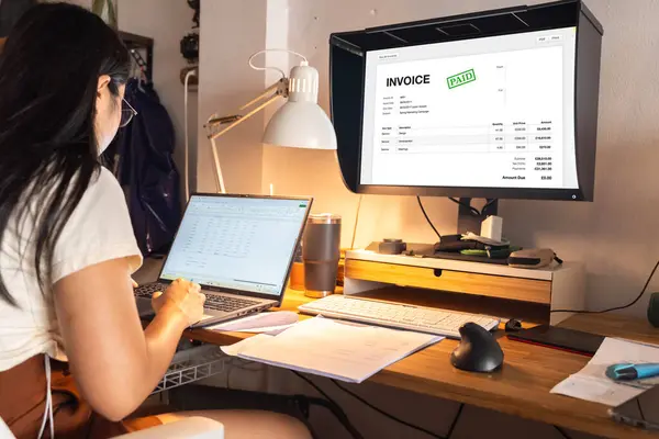 Accountant using E-invoice software at computer in office. Woman in office with sample invoice document on computer. Online Digital E Invoice Statement On Hybrid Laptop.