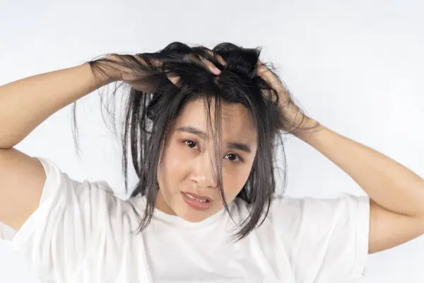 Broken hair, beautiful sad young woman with long disheveled hair, closeup photo of female model holding messy unbrushed dry hair in hand. Damaged hair health and beauty high resolution concept.