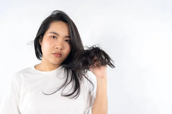 Young black woman with messy hair on white background. Asian women are worried about their damaged hair causing a lack of confidence. Hair loss treatment concept, damaged hair, beauty salon.