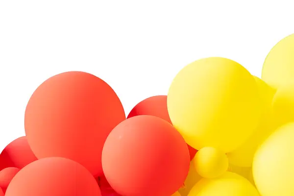 A bunch of red and yellow balloons floating on a white background. The balloons are of different sizes and are tied together in a cluster. There are light reflections on the balloons.