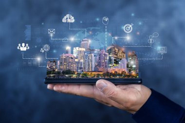 İnsan eliyle akıllı şehir kavramındaki bulut teknolojisi megapolis şehrinin gökdelenleri ile dijital tablet taşır ve bulutlu arkaplanda dijital sosyal ağ sembolleri bulunur..
