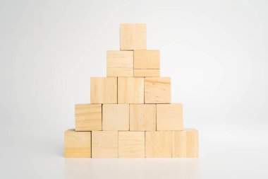 Boş boş tahta küp bloklar piramit şeklini oluşturur. Üstünde büyük olan beyaz arka plandaki ahşap masada izole edilir. İş büyüme süreci, eğitim, başarı binaları ve organizasyon kavramları.