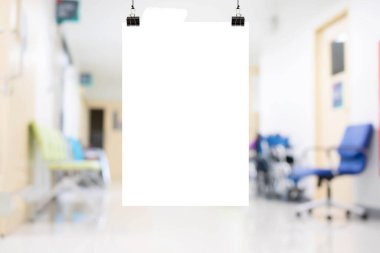 Mockup A4 white paper or white promotion poster displayed in medical clinic or hospital. Blurred ICU room in a hospital with medical equipments and patient.