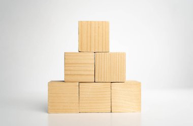 Boş boş tahta küp bloklar piramit şeklini oluşturur. Üstünde büyük olan beyaz arka plandaki ahşap masada izole edilir. İş büyüme süreci, eğitim, başarı binaları ve organizasyon kavramları.