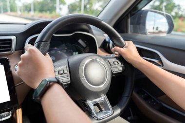 Araba kullanırken direksiyon tutan bir kadın el. Kırsal alanda araba kullanırken araba direksiyonu tutan beyaz kadın elleri, seçici bir odak noktası.