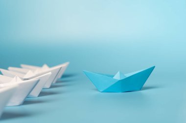 Paper Boats Liderlik Konsepti. Beyazlar arasında öncülük eden mavi kağıt gemiyle liderlik kavramı. Başarı, mavi lider botu beyaza öncülük ediyor, strateji planlama gelişimi.