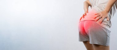 Woman hand holding her bottom because having Abdominal pain and Hemorrhoids, Health care concept. Woman suffering from hemorrhoids, anal pain. A woman holds his hands to the ass feeling pain.