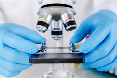 Laboratuvarda mikroskop kullanan bilim adamı tıbbi testler ve araştırmalar yapıyor. Laboratuvarda metal mercekle mikroskobun yakın çekim görüntüsü..