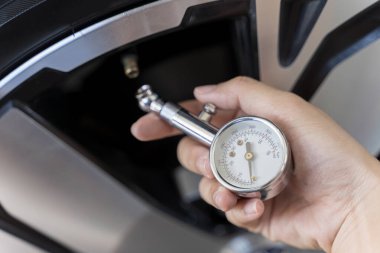 Lastik servisi atölyesindeki yeni bir tekerleğin lastik basıncı göstergesi. El arabası lastiklerini kontrol ediyor, arabasının lastiklerini kontrol ediyor. Sürüş ve sürüş güvenliği kavramı.