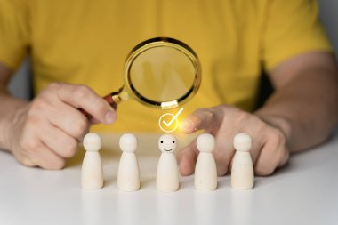 İnsan kaynakları (HR), işe alım, seçim, işe alım, CRM, doğru insanlar ve eşsiz kavramlar. Tahta figürlerin üzerinde insan eli tutan büyüteç..