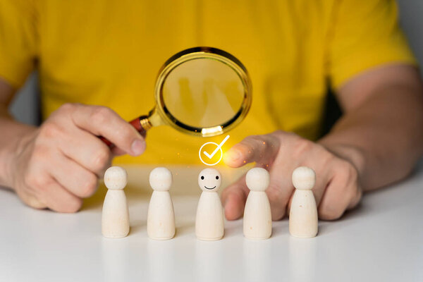 Human resource (HR), hiring, selection, recruitment, CRM, right people and unique concepts. Human Hand Holding Magnifying Glass Over Wooden Figures.