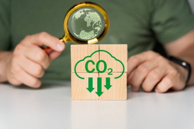 Küresel ısınmayı iklim değişikliğinden sınırlamak için CO2 'nin CO2, karbon ayak izi ve karbon kredisini azaltmak amacıyla doğadaki ahşap blok küp üzerindeki ikonu elle birleştirmesi, Bio Dairesel Yeşil Ekonomi kavramı.