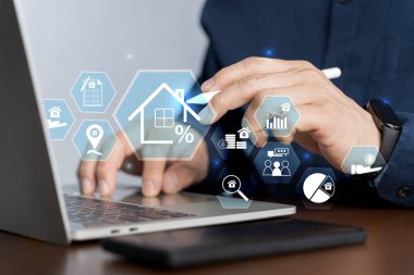 Gayrimenkul yatırım kavramı. Ev kredisini ve emlak kredisini analiz etmek için ev ikonu olan dizüstü bilgisayar kullanan bir adam. Faiz oranı, yatırım planlaması, iş yeri gayrimenkul.