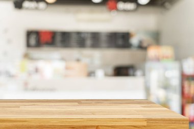 Tahta masa bulanık arkaplanın önünde boş. Kahverengi ahşap, bulanık kahve dükkanında. Ürünlerinizi görüntülemek veya montajlamak için kullanılabilir. Ürünün gösterimi için modelle.