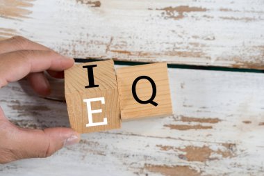 İş adamı eli ahşap küpü IQ 'dan EQ' ya, zeka seviyesi ve duygusal zeka kavramları arasındaki dengeyi değiştiriyor.