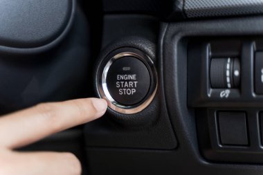 Kadın, arabadaki motoru çalıştırma / durdurma düğmesine basıyor. Arabayı çalıştırma düğmesine basarak çalıştırmaya çalışan birine yakın durun. Genç işadamının arabasındaki motoru çalıştırma görüntüsü..