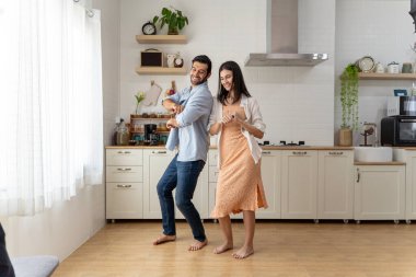 Aşık bir çiftin yeni evlerinin tadını çıkardığı harika bir aşk ve mutluluk sahnesi. Neşeli kadın ve erkek arkadaş evde dans ediyor. Romantik çift evde mutfakta dans ediyor..