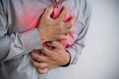 Kronik bir hastalıktan dolayı göğüs ağrısı çekiyordu. Göğüs ağrısı, kalp krizi konsepti. Genç adam kalp ağrısı çekiyor ve göğsünü eliyle tutuyor.