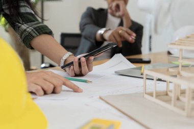 Ofiste mimari modeli elinde tutan kendine güvenen bir iş kadını. Veri çalışması ve tablet bilgisayar. Mimarın müşterilere proje planını açıklaması. İnşaat fikirleri oluşturma konusunda sonuç bul.