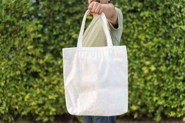 Sıfır israf yaşam tarzı konsepti. Adam boş şablon için çanta kumaşı tutuyor. Çanta, kumaş kumaş, alışveriş torbası modeli izole edildi. Yeniden kullanılabilir pamuk Eko üretim torbası. 