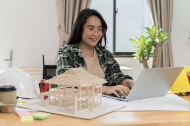 Veri çalışması ve tablet bilgisayar. Mimarın müşterilere proje planını açıklaması. Mimari modeli ofisinde tutan kendine güvenen bir iş kadını.. 