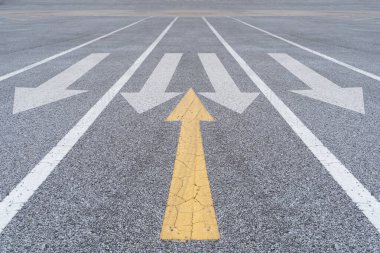 Farklı düşünceler ve iş ve teknoloji karışıklığı. Asfalt üzerinde beyaz okla kesişen sarı ok. 