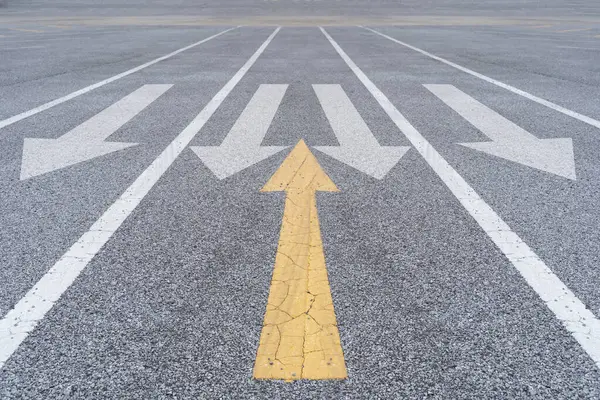Farklı düşünceler ve iş ve teknoloji karışıklığı. Asfalt üzerinde beyaz okla kesişen sarı ok. 