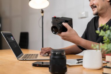  Genç profesyonel fotoğrafçı ev stüdyosundaki dizüstü bilgisayardaki fotoğrafları düzenlemekle meşgul. Genç sakallı fotoğrafçı evde fotoğraf düzenliyor. Ajans stüdyosunda çalışan foto muhabiri..