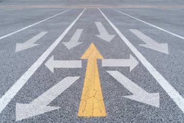 Sarı ok, asfalt caddesindeki beyaz okları ters yöne çeviriyor. Farklı düşünceler, bireysel ve ayakta duran kavramlar. Rekabetçi ortamlarda yaratıcılığı ve farklılığı simgeliyor.