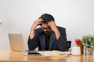 Dizüstü bilgisayarda çalışan bir iş adamı ve ofis sendromu. Bilgisayarın önünde çalışan küçük bir işadamının portresi faturaları ödemekten ya da verileri analiz etmekten başı ağrıyormuş..