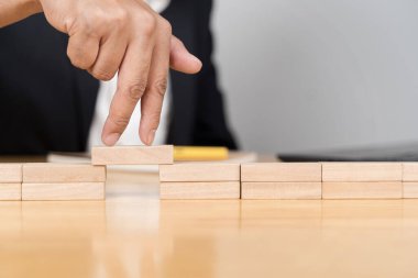 İş adamı sorunları çözüyor. İşadamı, tahta bloklar arasında risk altında yürüyor. Parmaklar, masanın tahta yüzeyinde yürüyen bacaklar gibi hareket eder..