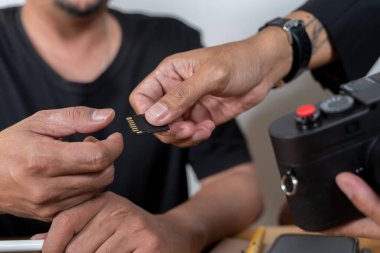 İki kişinin SD hafıza kartını değiş tokuş edişinin yakın çekimi. Bir el ve bir el kamerayla. Veri transferi, yedekleme, fotoğrafçılık iş akışı veya fotoğrafçılar arasındaki işbirliği kavramı.