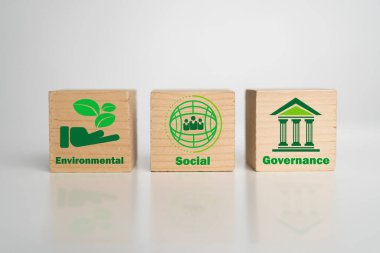 Yeşil simgeli üç tahta blok ESG ilkelerini sembolize etmektedir: Çevre, Sosyal ve Yönetim, kurumsal sürdürülebilirliği ve sorumlu iş uygulamalarını temsil etmektedir.