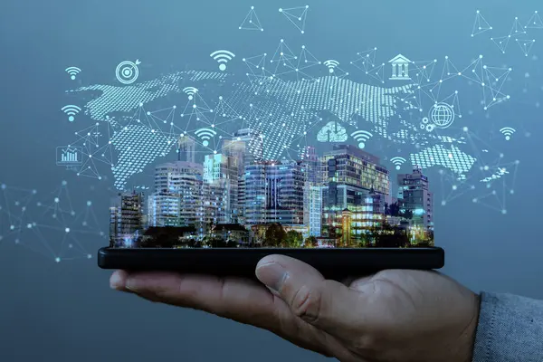 Akıllı şehir hologramı ve dijital bağlantı ikonlarıyla el ele tutuşan akıllı telefon. Nesnelerin internet kavramı, iletişim, büyük veriler, kentsel teknoloji ve gelecekteki altyapı.