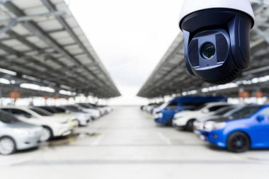 Güvenlik kamerası modern bir açık hava otoparkını izliyor. Arabalar güneş paneli çatısı altında sıra sıra park edilmiş. Gözetim, güvenlik ve akıllı park teknolojisi kavramı.