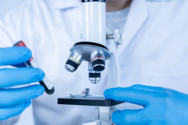 Laboratuvarda mikroskop altında kan örneğini inceleyen bilim adamı, tıbbi araştırma, sağlık kontrolü, mikrobiyoloji çalışması, yenilikçi teknoloji ve profesyonel bilimsel deneyi temsil ediyor.