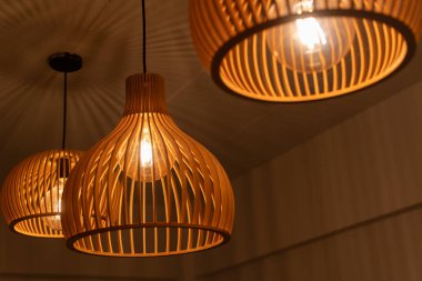 Sıcak, ahşap kolye lambaları tavandan sarkan rahat, modern ev içi, şık ve zarif ışıklandırma tasarımı doğal malzemeler kullanarak rahat ve sanatsal bir atmosfer yaratıyor.