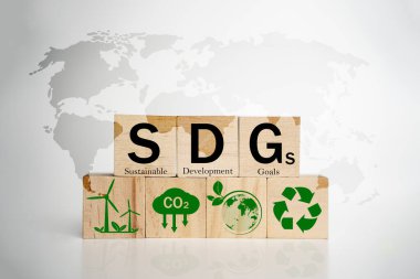Beyaz zemin üzerinde SDG yazılı tahta küpler ve ekolojik simgeler, sürdürülebilir kalkınma hedefleri, yenilenebilir enerji, karbon azaltma, geri dönüşüm, küresel çevre, gelecekteki yeşil iş görüşünü temsil eden