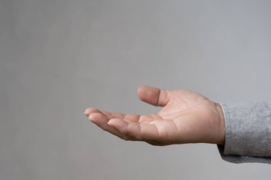 Gri arka planda izole edilmiş açık insan eli hareketi, güven, sosyal bağlantı kavramları için uygun, verme, destek, bakım, sorumluluk, yardım, bağış ve cömertliği sembolize eder..