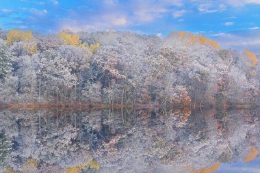 Long Lake kıyı şeridinin gündoğumunda sonbahar manzarası karla kaplandı ve sakin sularda yansımalar görüldü, Yankee Springs State Park, Michigan, ABD