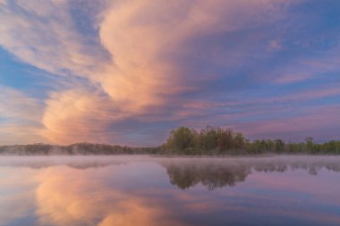Whitford Gölü kıyılarının şafağında sisli bahar manzarası sakin sularda yansıyan yansımalarla, Fort Custer State Park, Michigan, ABD