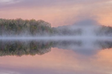 Foggy spring landscape at dawn of Moccasin Lake with mirrored reflections in calm water, Hiawatha National Forest, Michigan's Upper Peninsula, USA clipart